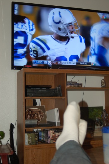 Football on TV with feet propped up. Finally, a chance to rest and recuperate after an exhausting few weeks spent moving. (Photo by John G. Miller)